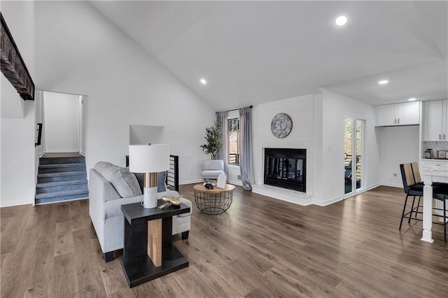 living room featuring a large fireplace, lofted ceiling, and hardwood / wood-style flooring