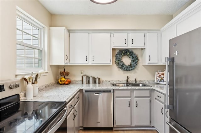 kitchen featuring light stone counters, appliances with stainless steel finishes, sink, and white cabinets