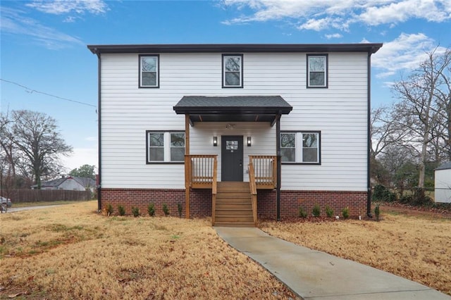 traditional-style home with brick siding, a front yard, and fence