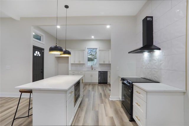 kitchen featuring light wood-type flooring, black appliances, a sink, tasteful backsplash, and wall chimney range hood