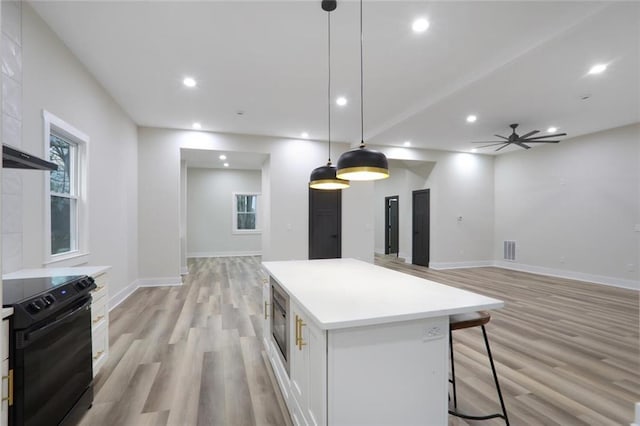 kitchen featuring a center island, recessed lighting, black / electric stove, white cabinets, and light countertops