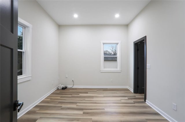 spare room featuring recessed lighting, light wood-style floors, baseboards, and a wealth of natural light