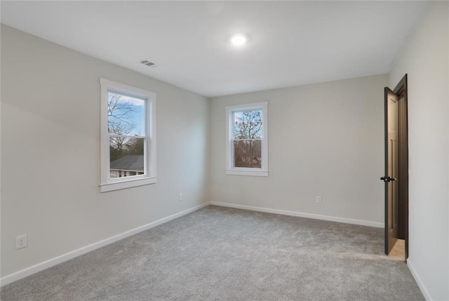 carpeted empty room featuring visible vents and baseboards