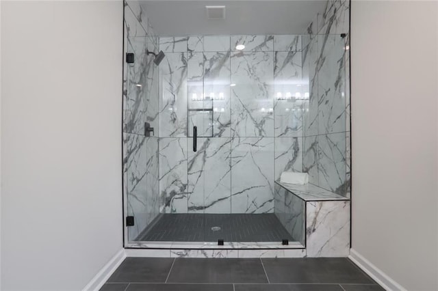 full bathroom with a marble finish shower, tile patterned flooring, and baseboards