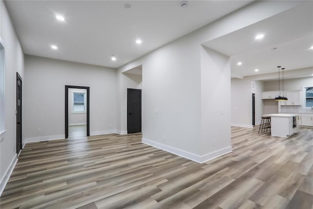 unfurnished living room with recessed lighting, baseboards, and light wood-style floors