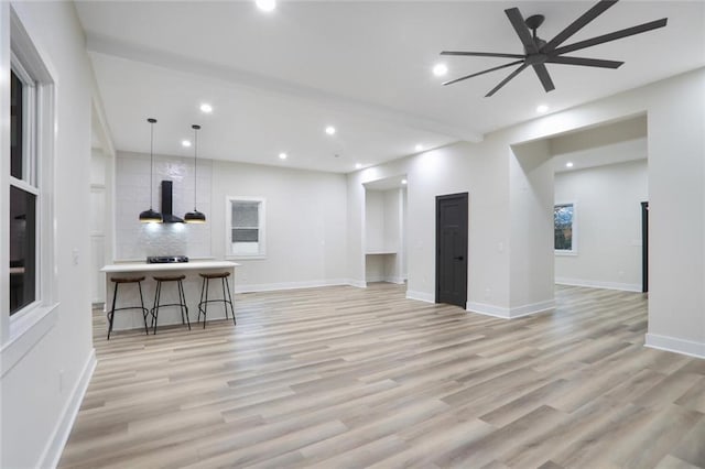 unfurnished living room with light wood finished floors, recessed lighting, and baseboards