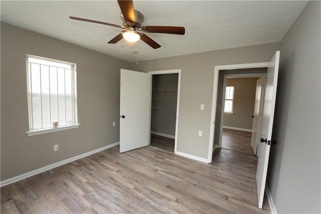 unfurnished bedroom featuring a ceiling fan, a closet, light wood-style flooring, and baseboards