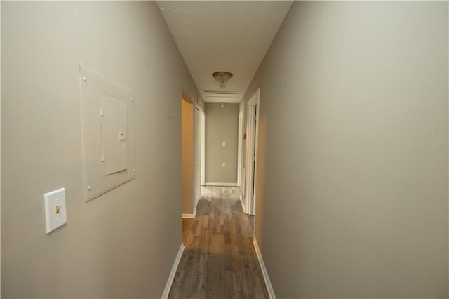 hallway with dark wood-style floors, electric panel, and baseboards