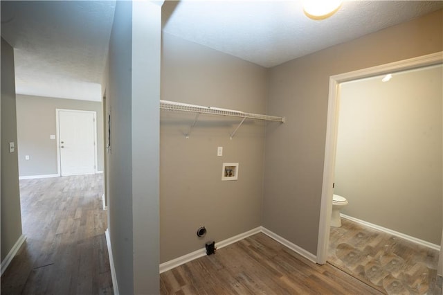 clothes washing area with a textured ceiling, hookup for a washing machine, laundry area, wood finished floors, and baseboards