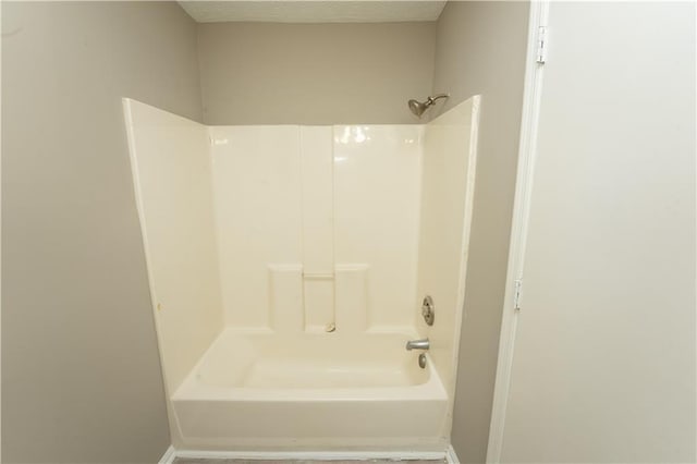 bathroom featuring a textured ceiling, shower / washtub combination, and baseboards