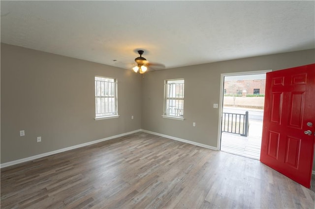 empty room featuring a ceiling fan, baseboards, and wood finished floors