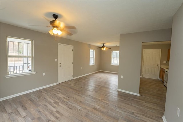 unfurnished living room with light wood-type flooring, ceiling fan, and baseboards