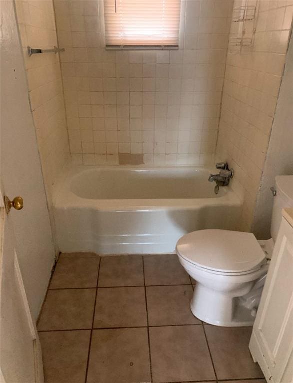 full bathroom with tile patterned flooring, tiled shower / bath, vanity, and toilet