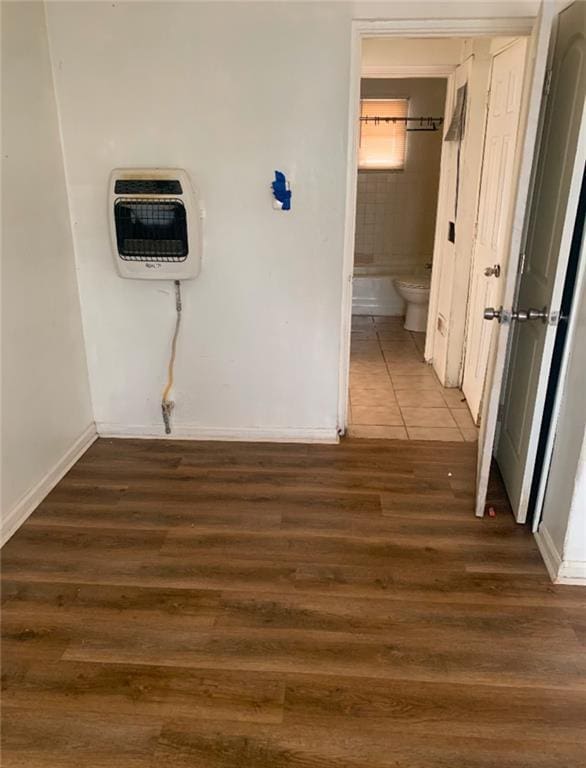 corridor with dark hardwood / wood-style flooring and heating unit