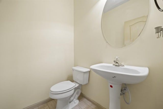 half bath with baseboards and toilet