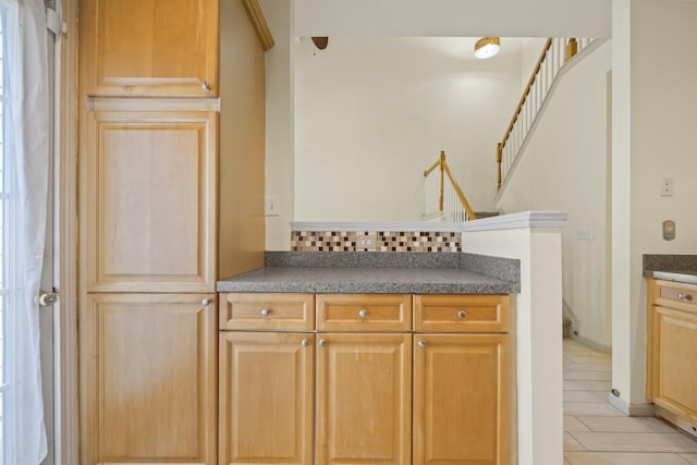 interior space with light tile patterned flooring, stairway, and tasteful backsplash