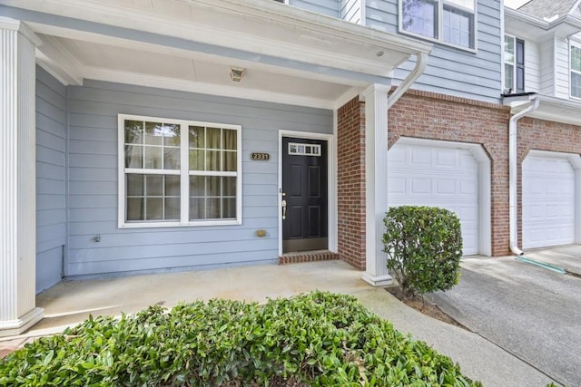 view of exterior entry featuring brick siding and a garage