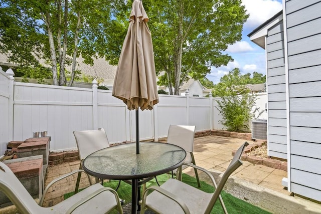 view of patio / terrace with central AC unit, outdoor dining space, and a fenced backyard