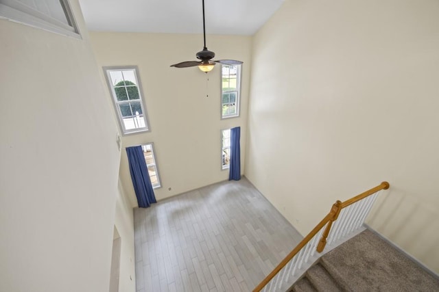 foyer featuring a towering ceiling, ceiling fan, and light wood finished floors
