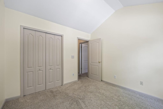unfurnished bedroom featuring a closet, baseboards, carpet flooring, and lofted ceiling