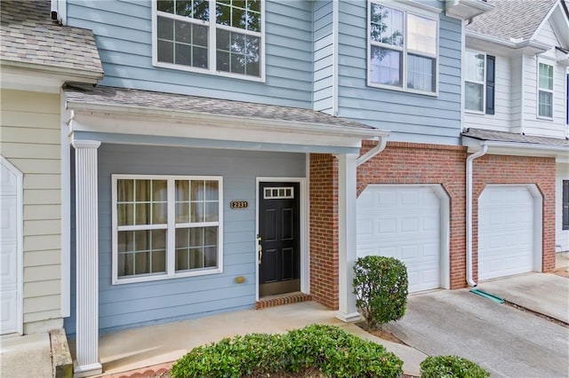 property entrance featuring brick siding, an attached garage, and driveway