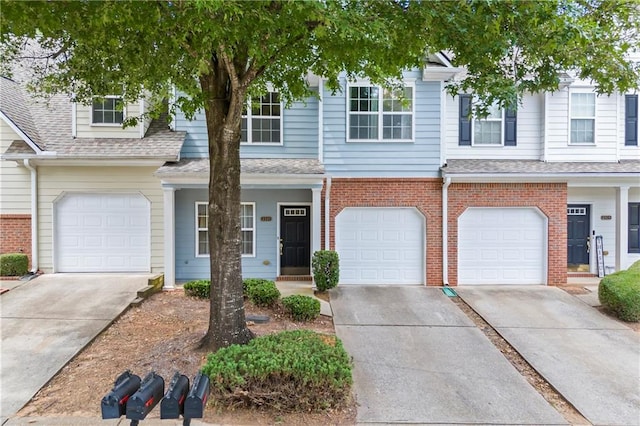 townhome / multi-family property with a garage, a shingled roof, driveway, and brick siding