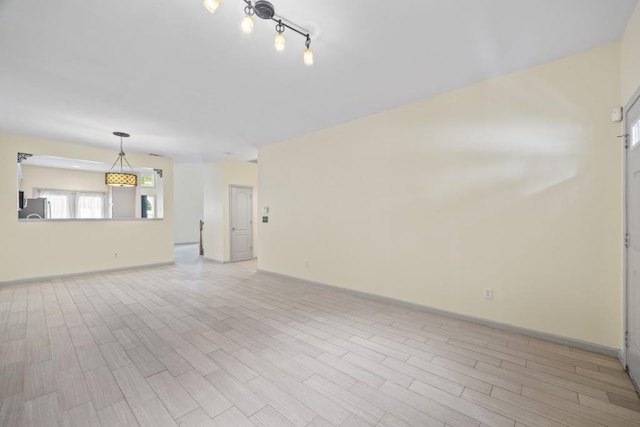 spare room featuring baseboards and light wood-type flooring