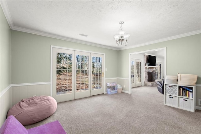 living area featuring a textured ceiling, an inviting chandelier, crown molding, and carpet flooring