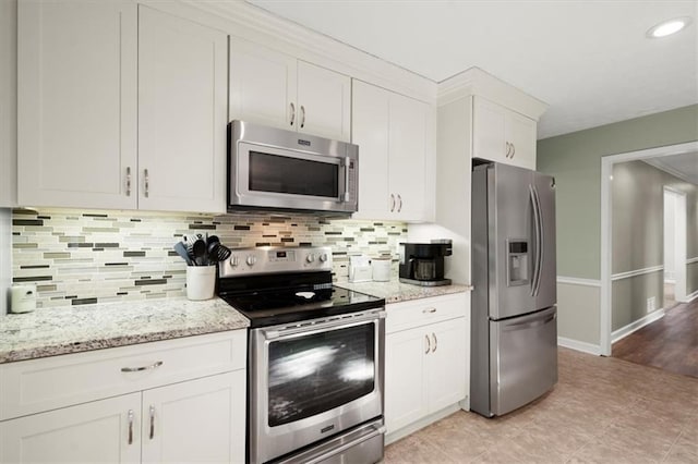 kitchen featuring backsplash, stainless steel appliances, light stone counters, white cabinets, and light tile patterned flooring