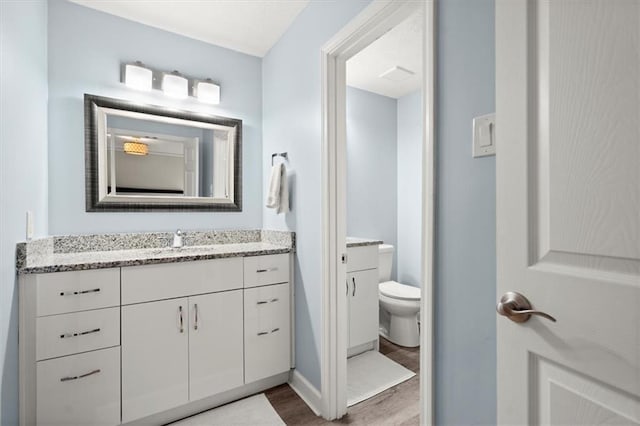 bathroom with toilet, wood-type flooring, and vanity