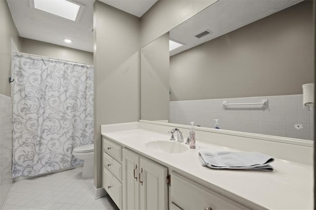 bathroom featuring toilet, tile patterned floors, tile walls, and vanity