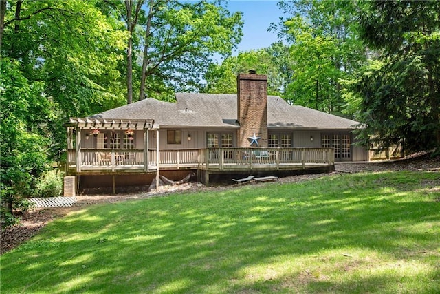 rear view of property with a pergola, a wooden deck, and a lawn