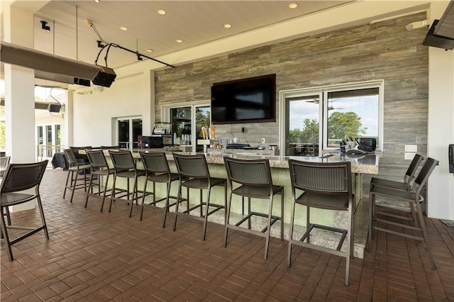 interior space featuring a high ceiling, wooden walls, and light stone counters