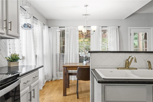 clothes washing area featuring an inviting chandelier, light wood-style flooring, visible vents, and a sink