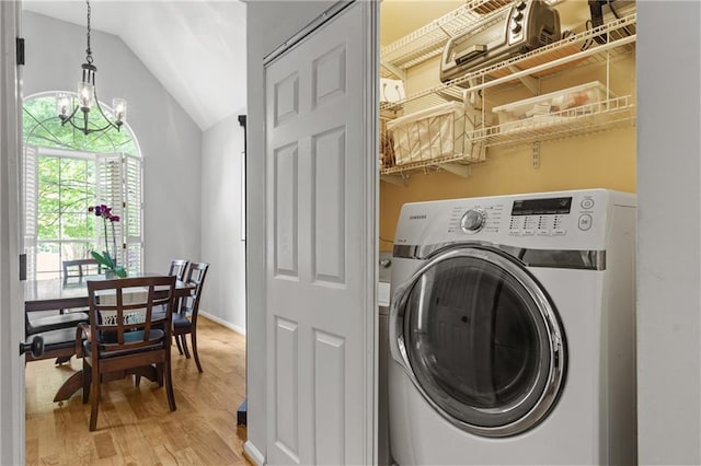 laundry room with laundry area, light wood finished floors, washer / dryer, and an inviting chandelier