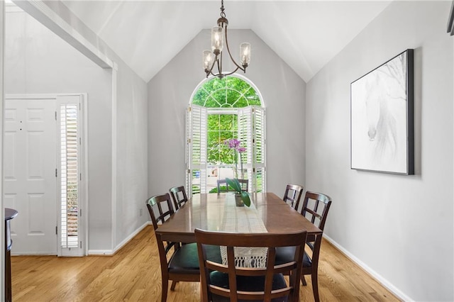 dining area with light wood-style floors, baseboards, lofted ceiling, and a notable chandelier