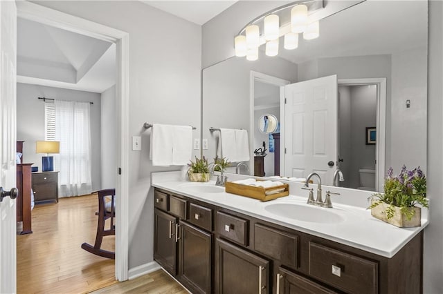 bathroom featuring a sink, double vanity, toilet, and wood finished floors