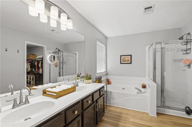 bathroom featuring a stall shower, a garden tub, visible vents, and a sink