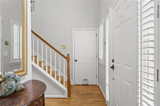 foyer with a wealth of natural light, stairway, and light wood-style flooring