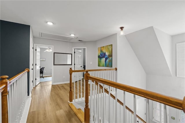 hallway featuring light wood finished floors, an upstairs landing, attic access, baseboards, and recessed lighting