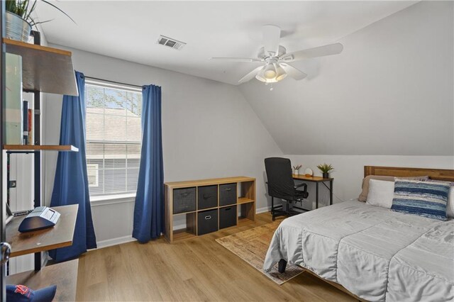 bedroom with wood finished floors, visible vents, vaulted ceiling, a ceiling fan, and baseboards