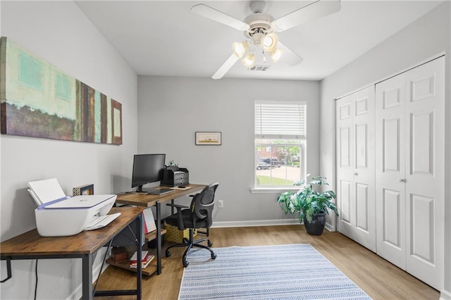 office space with light wood-type flooring, visible vents, baseboards, and a ceiling fan
