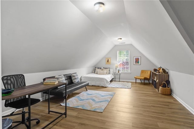 bedroom featuring wood finished floors, baseboards, and lofted ceiling