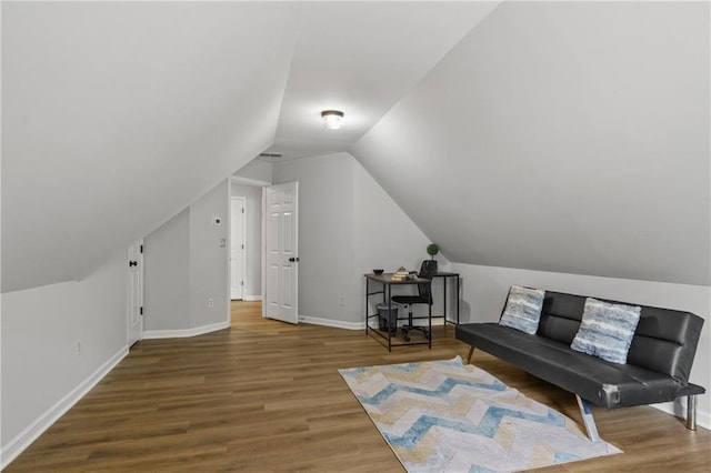 interior space featuring baseboards, vaulted ceiling, and wood finished floors