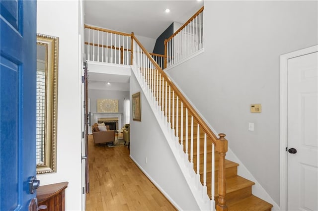 staircase featuring a fireplace, recessed lighting, and wood finished floors