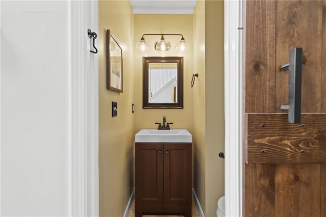 bathroom with baseboards, vanity, and toilet