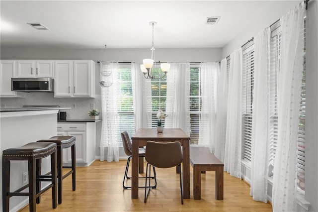 dining room featuring an inviting chandelier, light wood-style floors, and visible vents