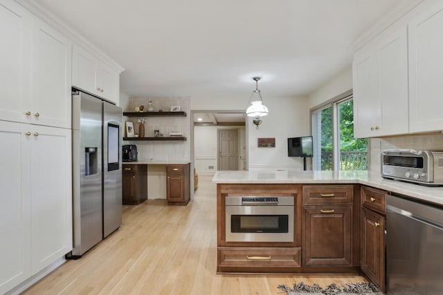 kitchen with a toaster, light countertops, decorative backsplash, appliances with stainless steel finishes, and white cabinetry