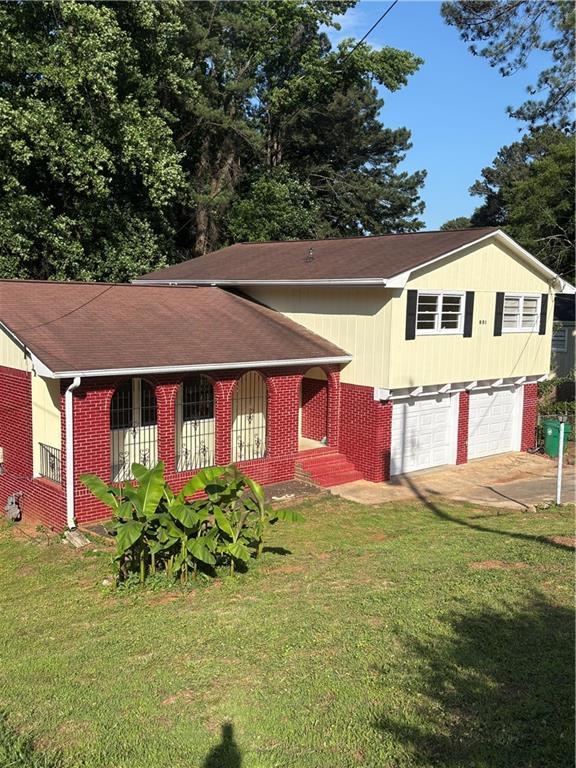 801 Needle Rock Dr, Stone Mountain, GA 30083 - view of front facade with brick siding, concrete driveway, a front yard, an attached garage, and a shingled roof