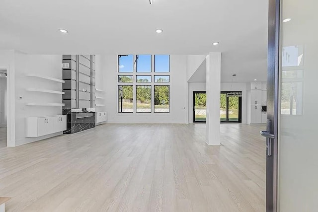 unfurnished living room featuring a wealth of natural light and light hardwood / wood-style floors